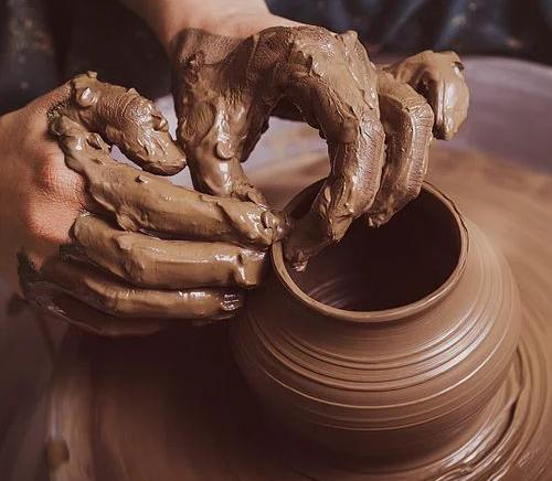 Hands shaping a clay pot on a pottery wheel